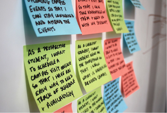 A group of colorful post-it notes on a wall with user stories written on them