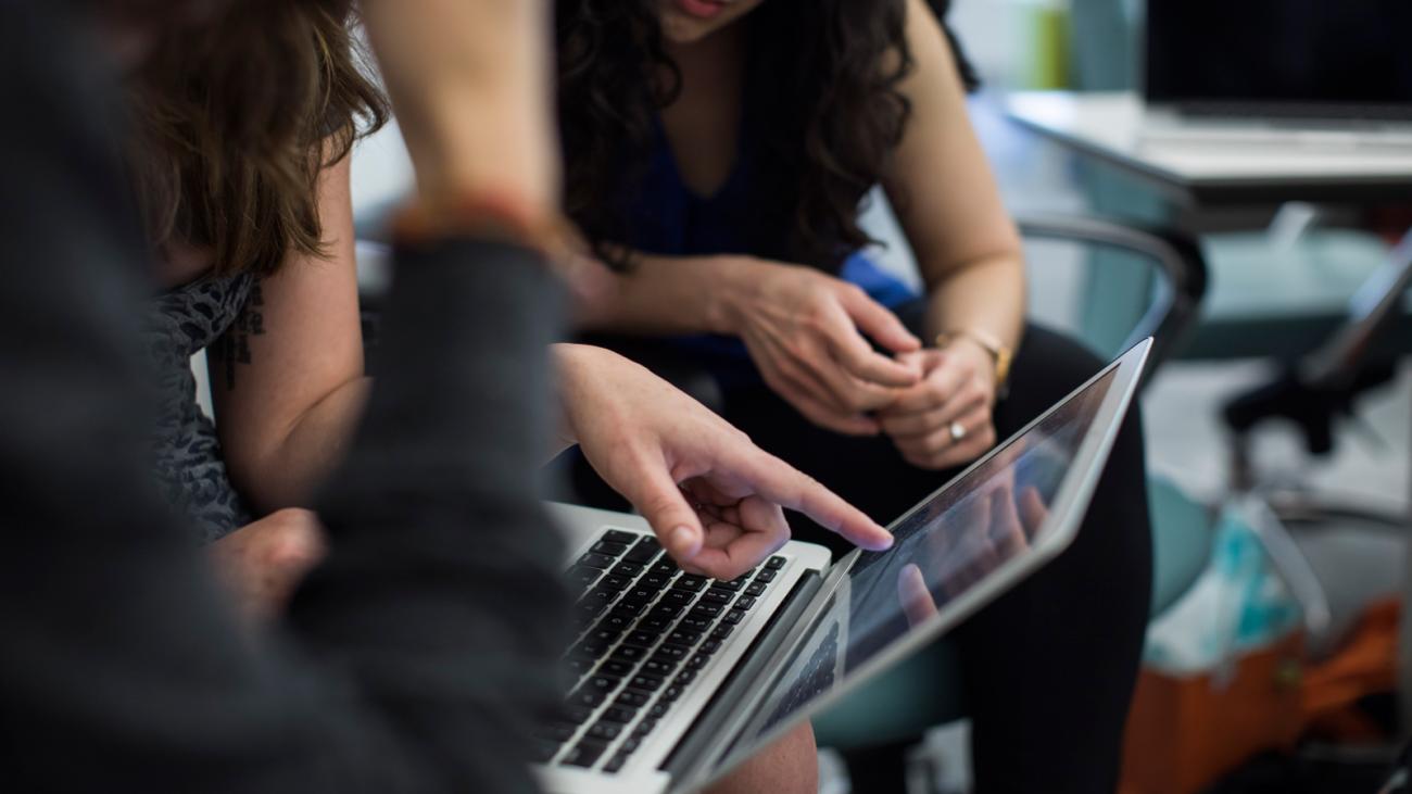 Person demonstrating something on a laptop to another person