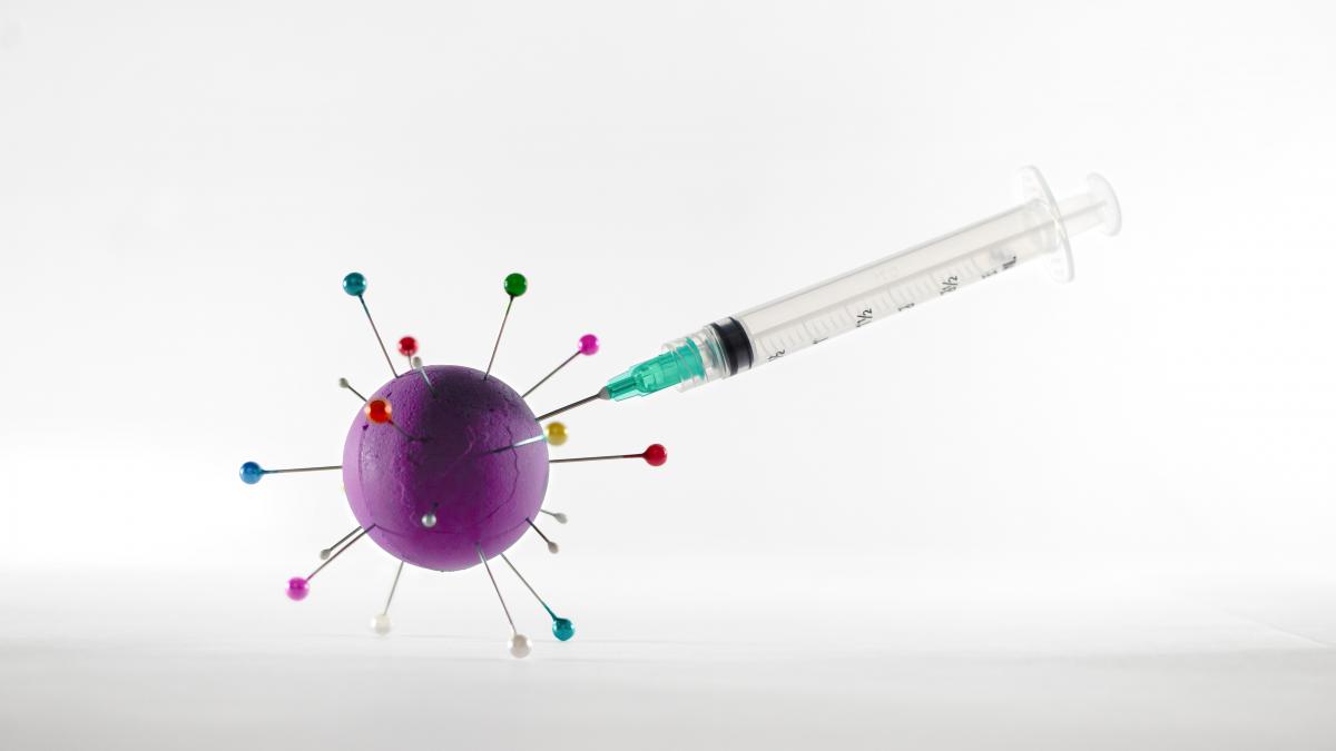 Image of a vaccine needle injecting a model of a virus