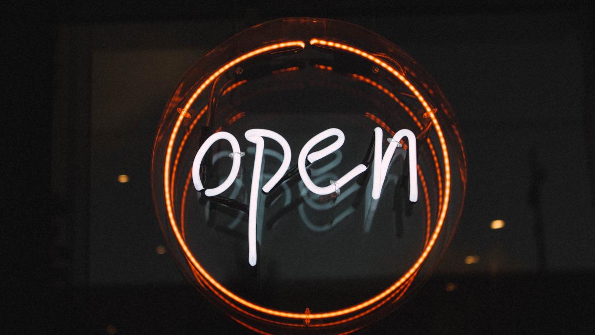 Photo of a neon sign reading "open" in white letters surrounded by an orange circle.