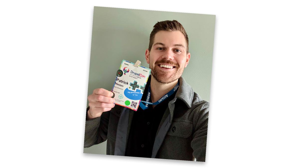 Selfie of Patrick Weston holding up his DrupalCon badge and smiling