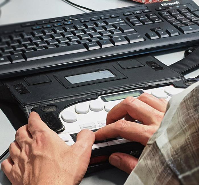 A person using a braille keyboard at a workstation