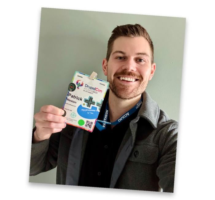 Selfie of Patrick Weston holding up his DrupalCon badge and smiling