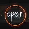 Photo of a neon sign reading "open" in white letters surrounded by an orange circle.