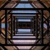 A view looking up at the underside of a building with a large bell in the center.